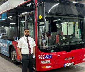 Fachkraft im Fahrbetrieb Laxay Kapoor vor einem Bus
